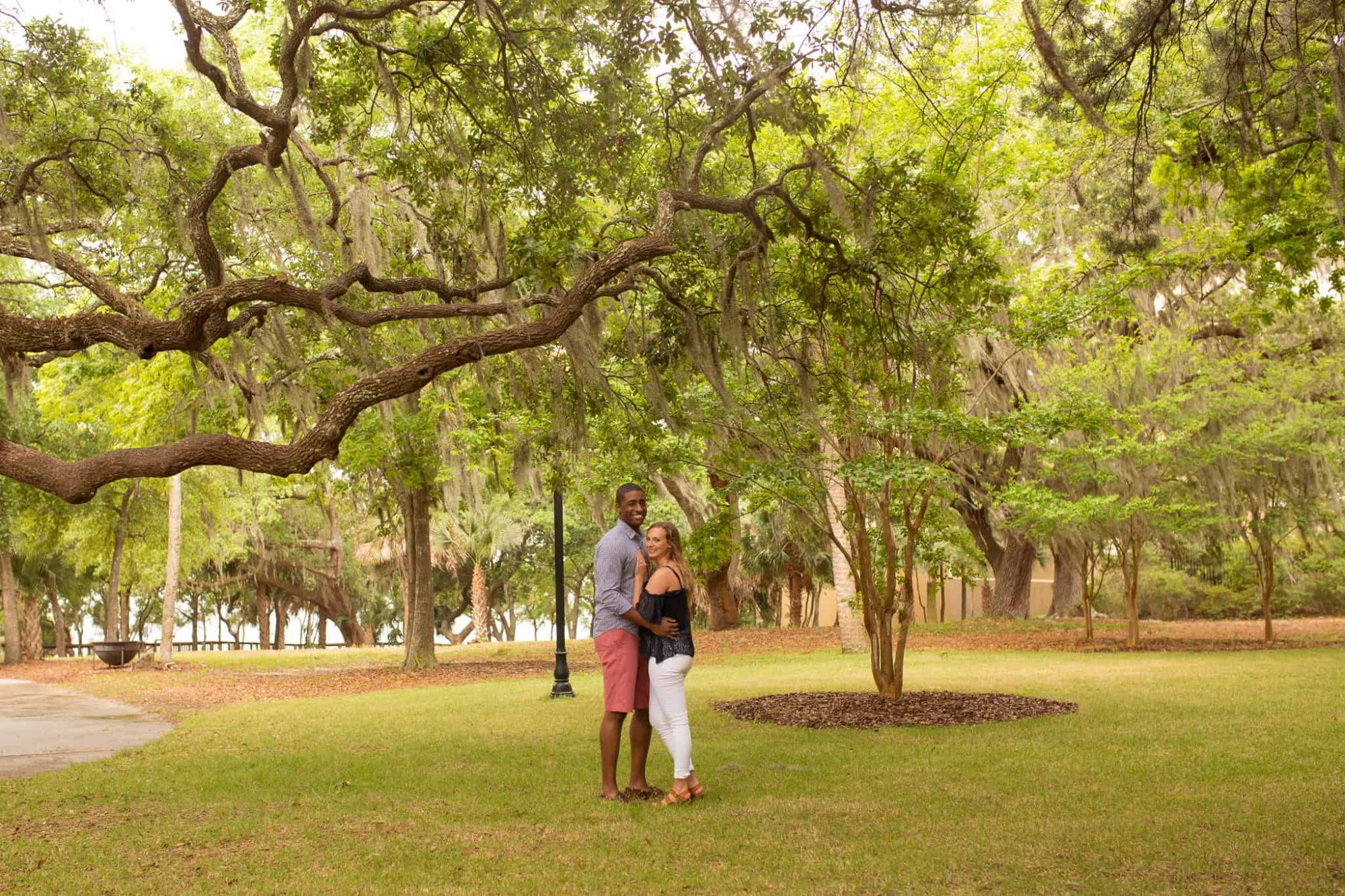 A couple hugging under an old oal stree covered in spanish moss.