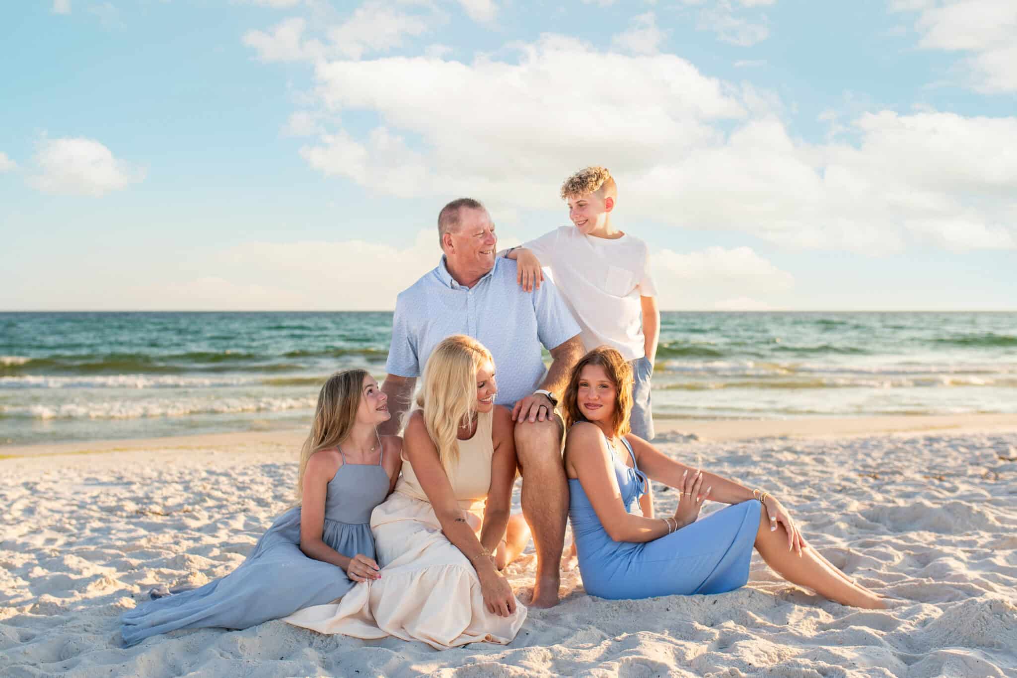 A family photo of 5 on th e beach. Mom, dad, 2 daughters, and their son