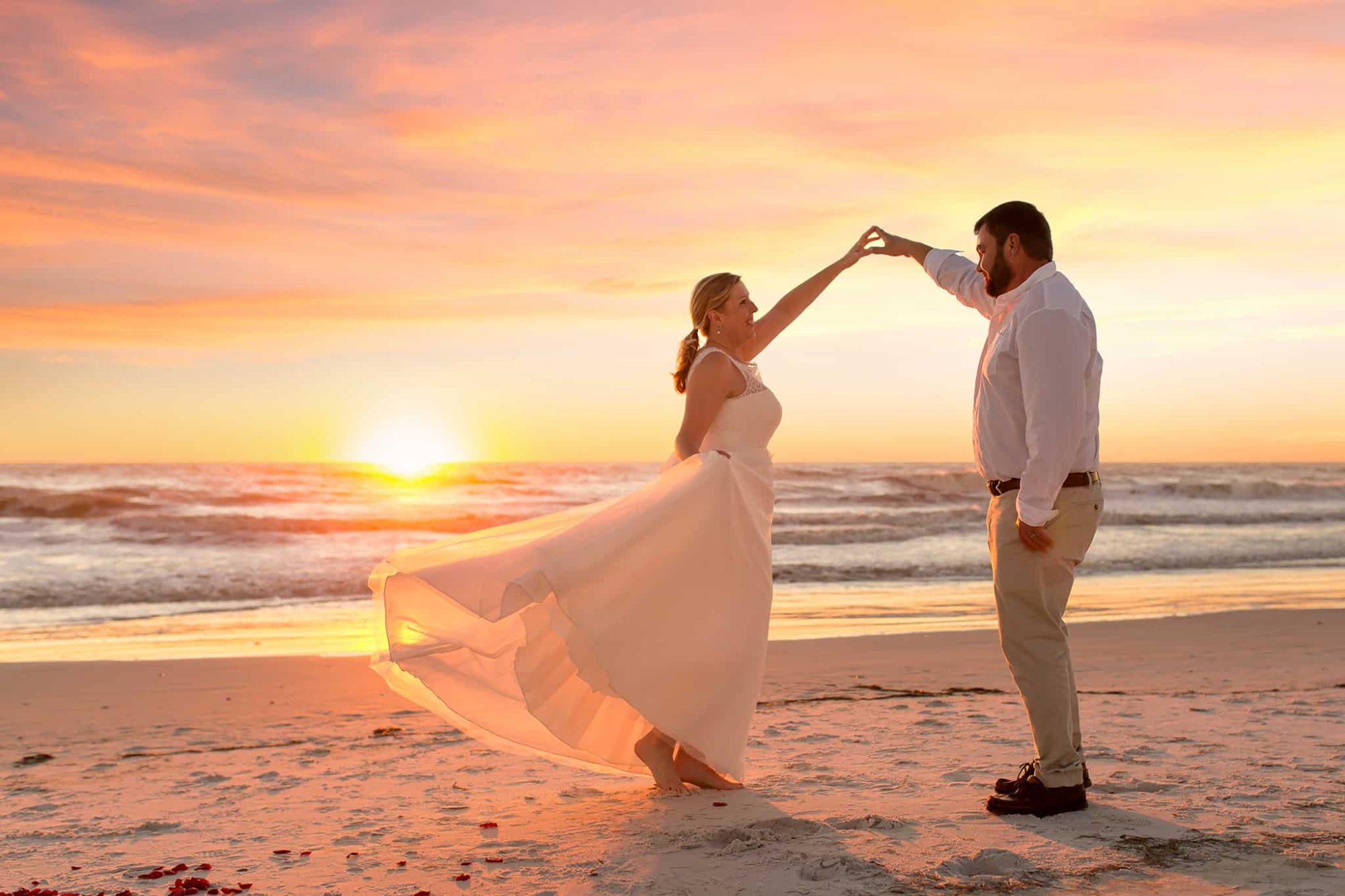 An elopement couple dancing on the beach at sunset