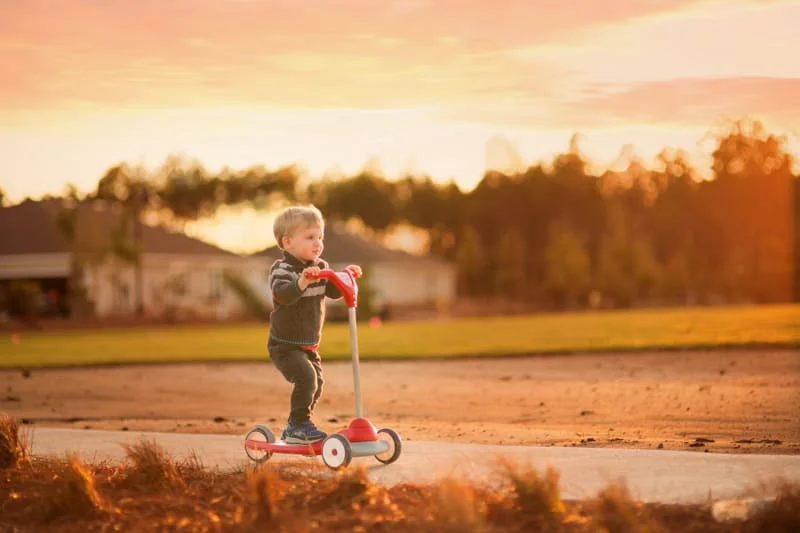A young boy riding his scooter
