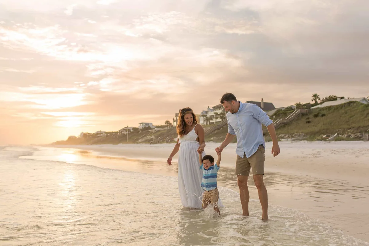 A mother and father playing with their son at the beach's shoreline