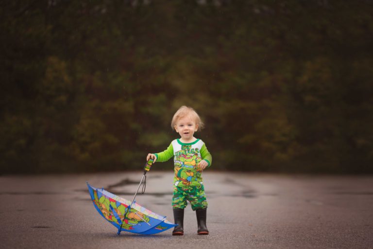 A child in galoshes, playing with an umbrella