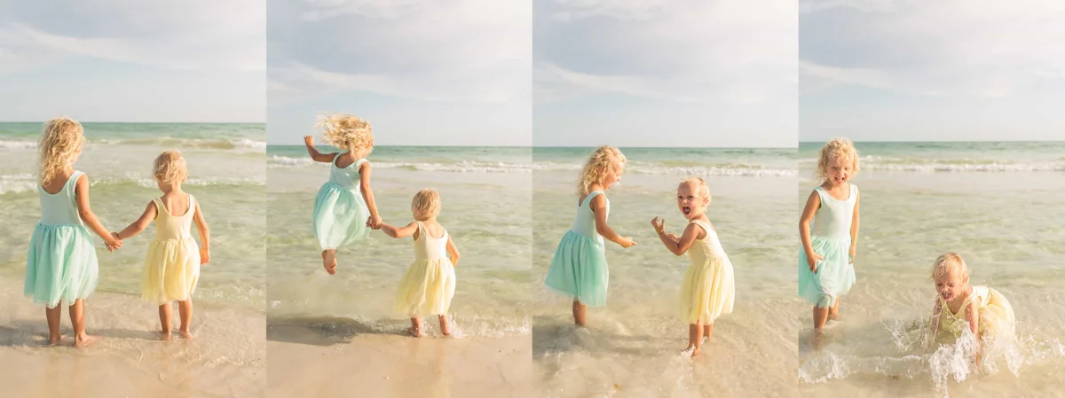 Two sisters playing in the water at the shoreline of the beach. The older girl is in a pastel teal dress. The younger girl is in a pastel yellow dress.