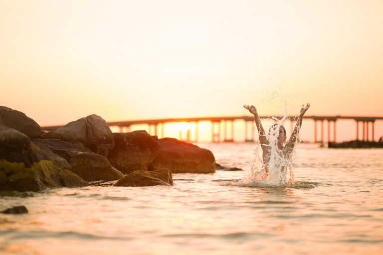 A young boy jumping out of the water in during the Golden Hour