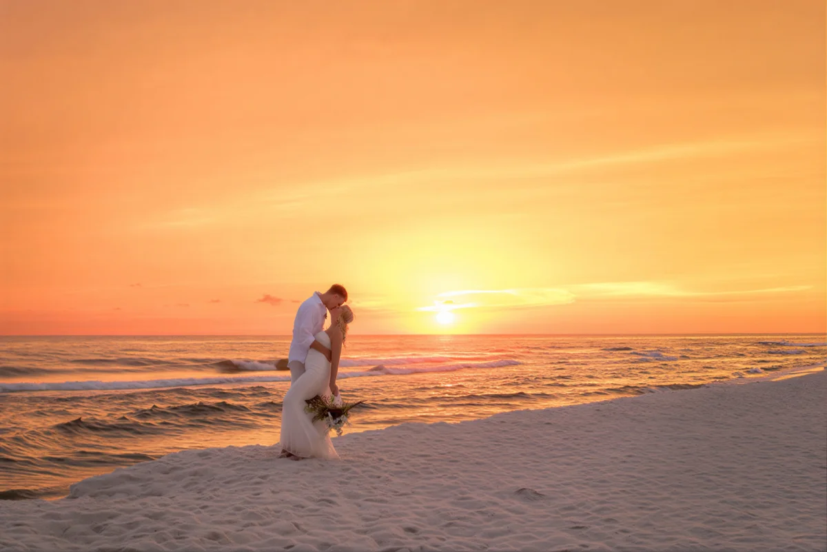 Romantic wedding photo of husband and wife at sunset on the beach